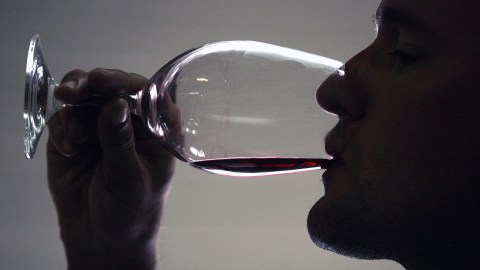 A man savoring a glass of red wine.