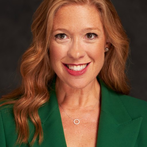 A woman in a green blazer smiling.