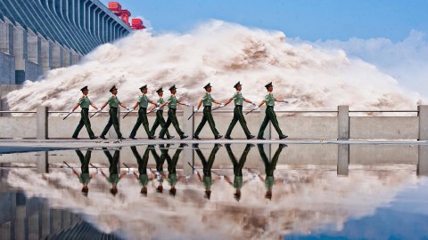 A group of soldiers standing in front of a large wave at Banqiao Dam.