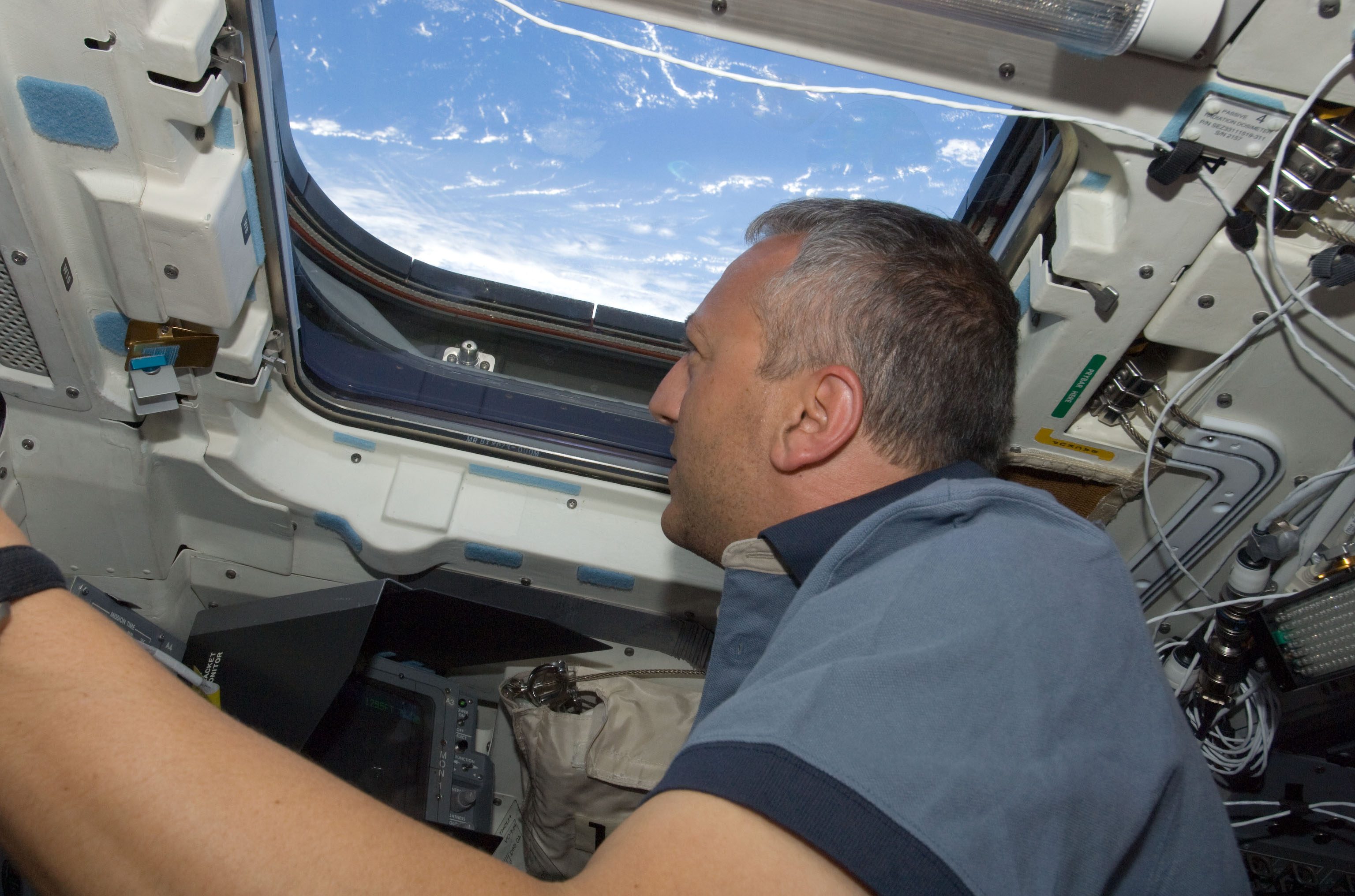 A man looking out of the window of a spacecraft.
