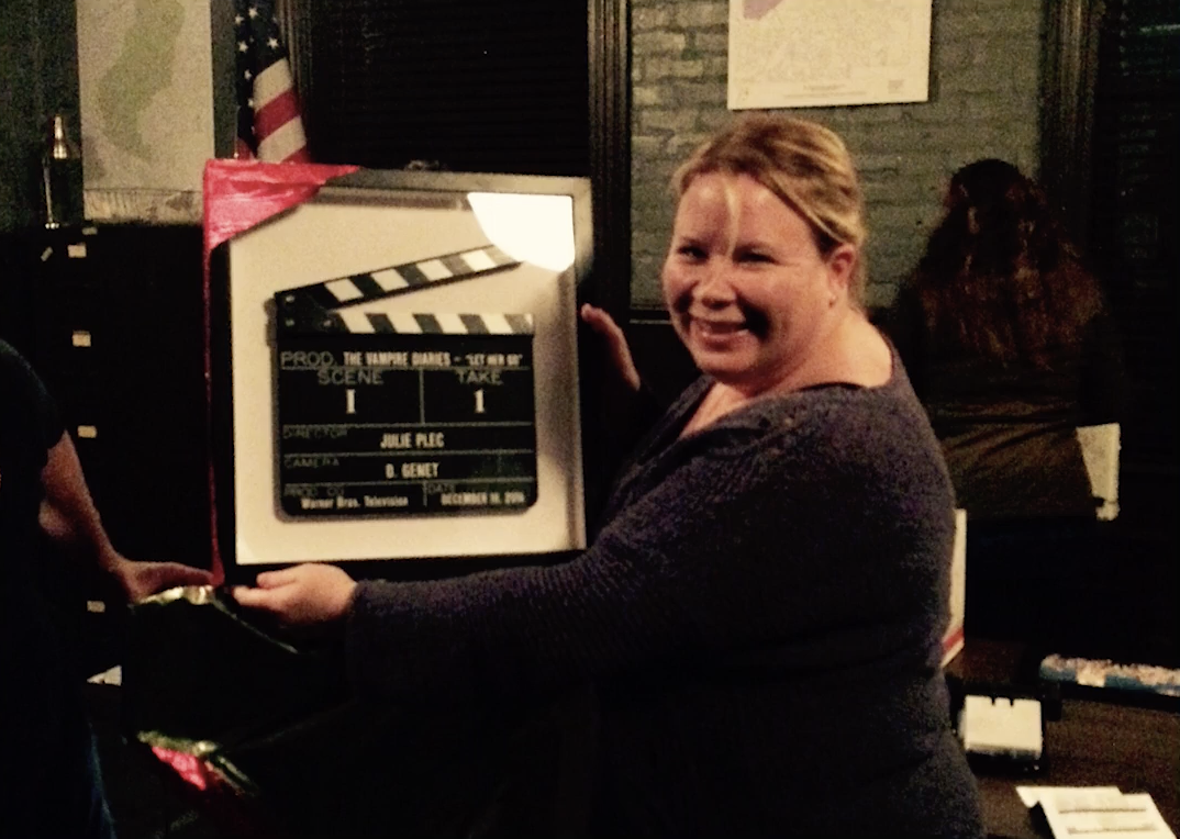 A woman holding up a clapper board in front of a group of people.