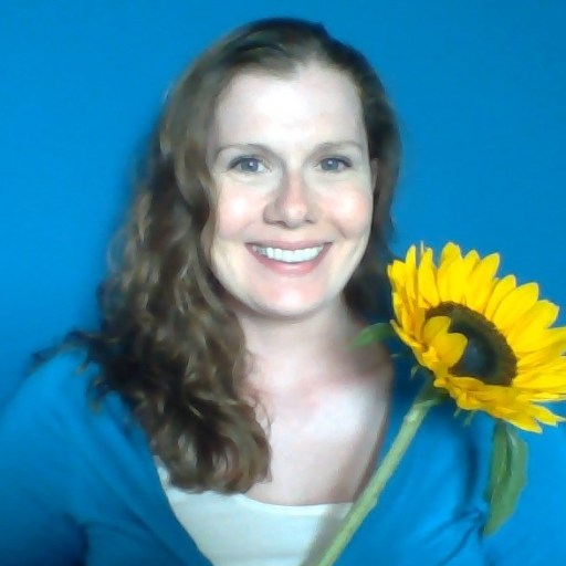 A woman holding a sunflower in front of a blue background.
