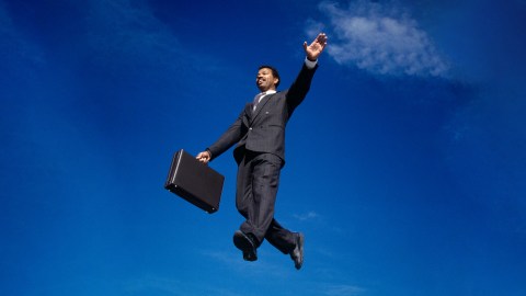 A man in a suit experiencing eudaimonic happiness while jumping in the air with a briefcase.