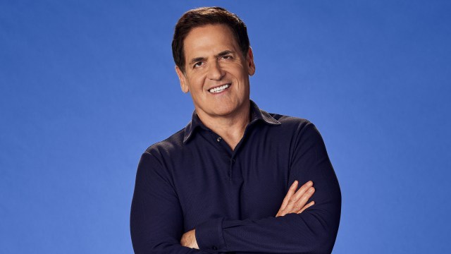 A successful man standing with his arms crossed in front of a vibrant blue background.