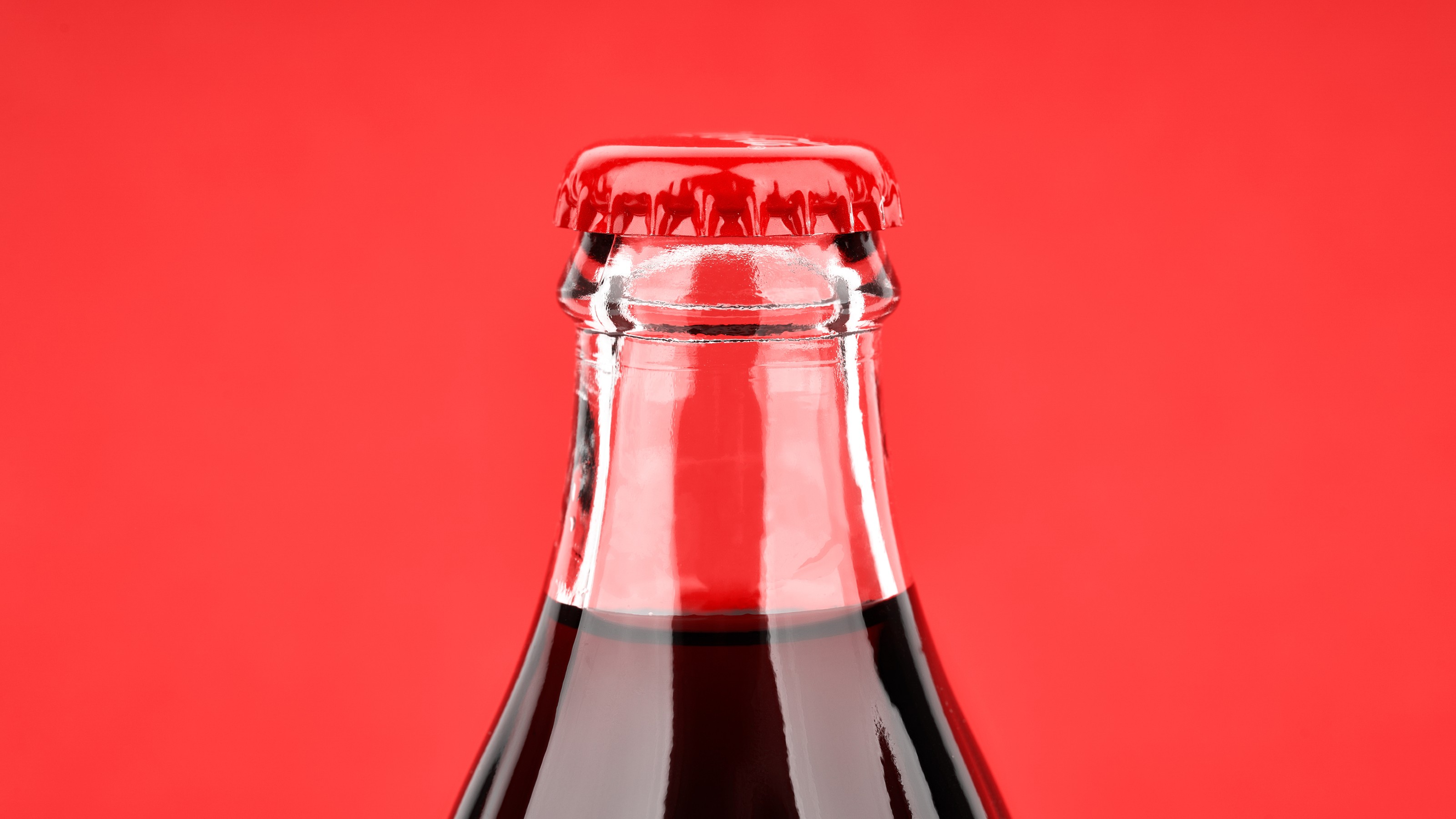 A bottle of Coca Cola on a red background.