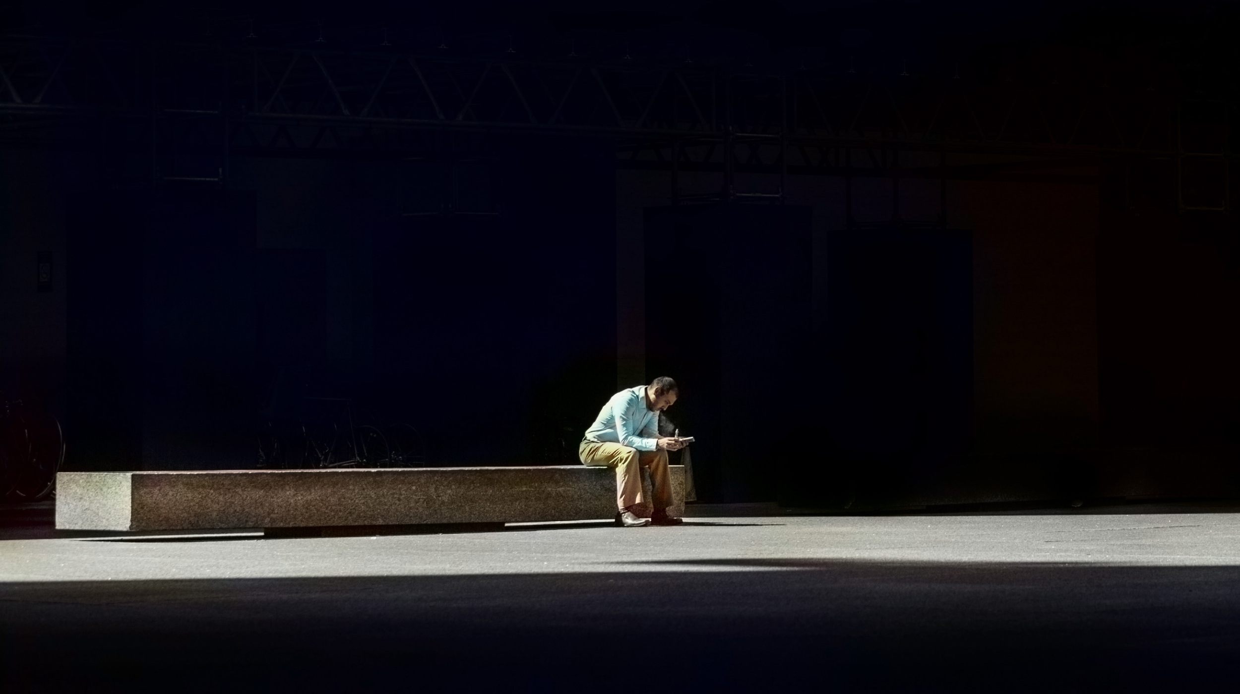 A man sitting on a bench in the dark.