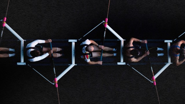 A group of people collaborating and showcasing trust as they sit together on a rope, against a captivating black background.