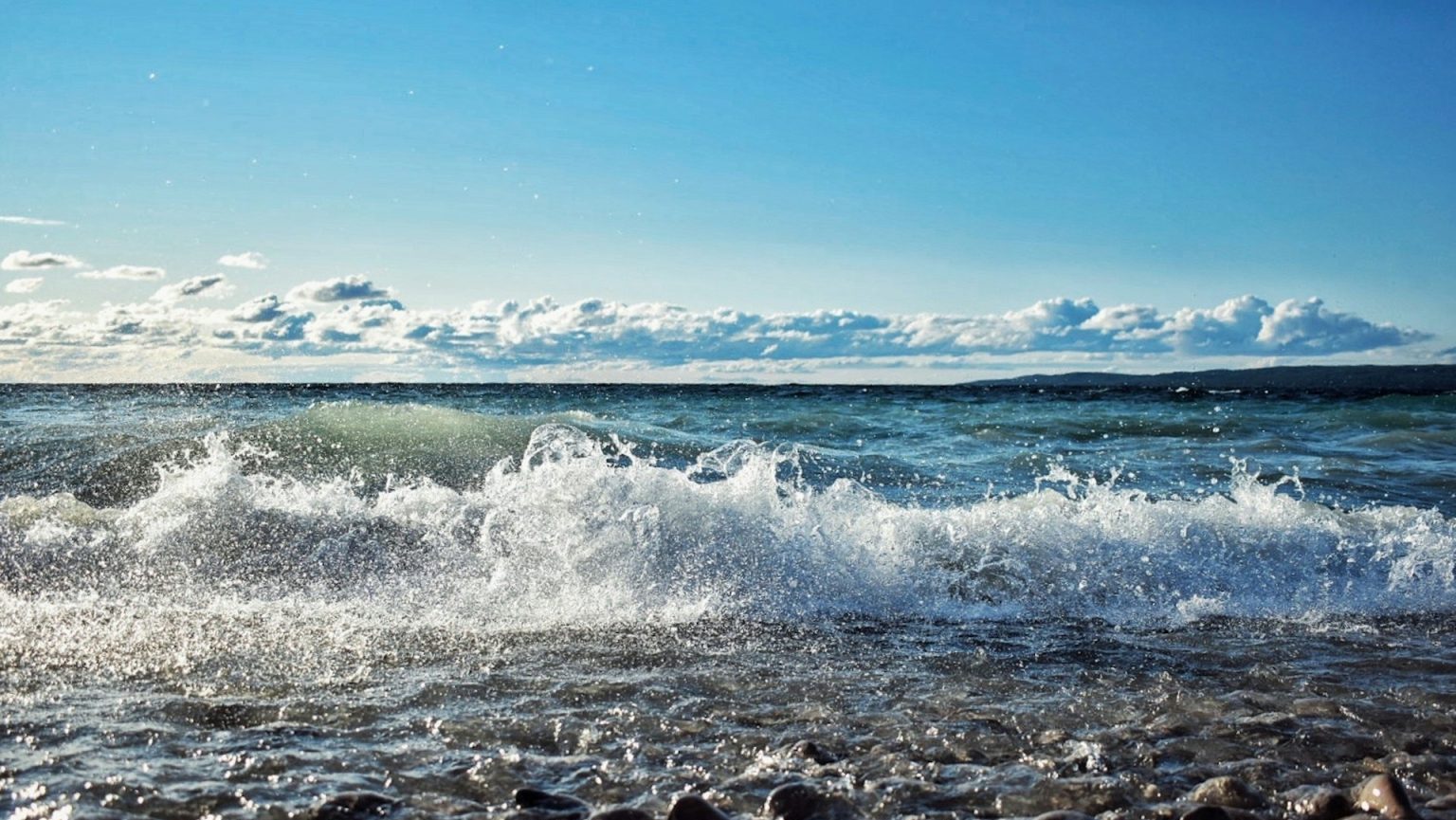 A beach along the Great Lakes with waves crashing over rocks and sand.