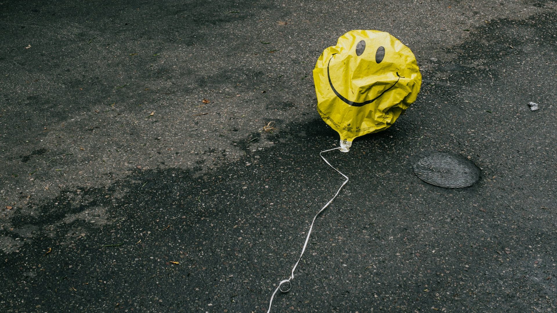 A yellow balloon lying on the ground in front of a car.