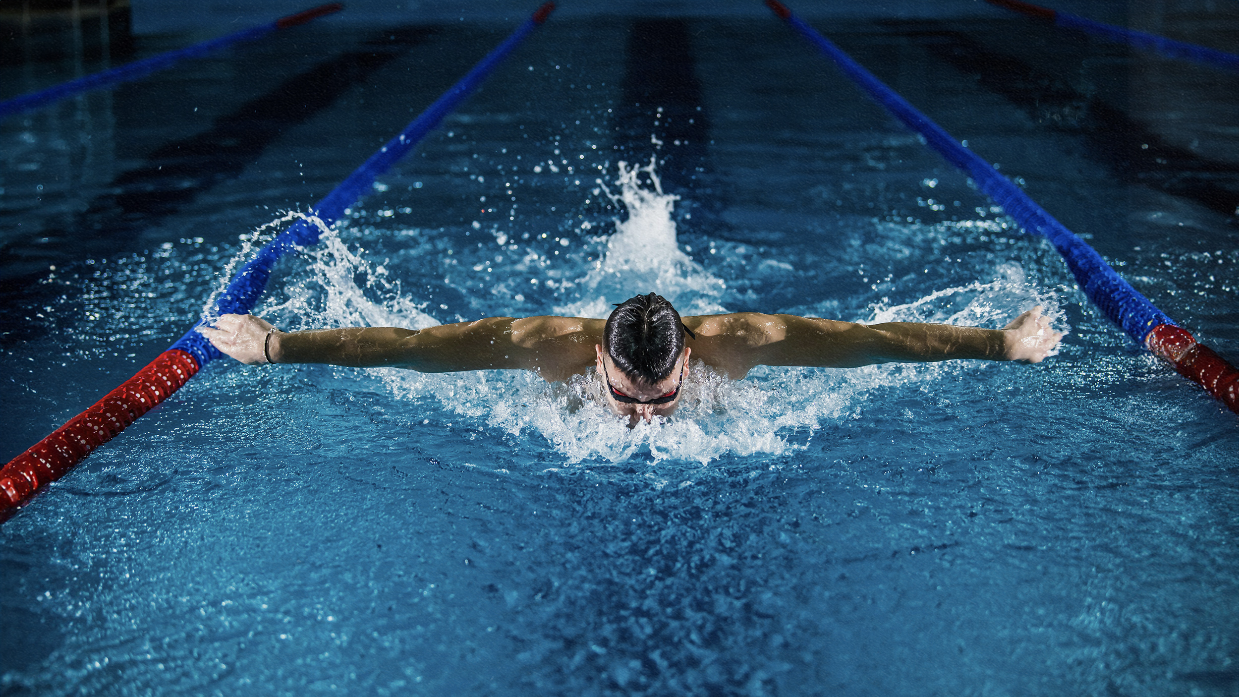 A swimmer is utilizing psychology for success while swimming in a pool at night.