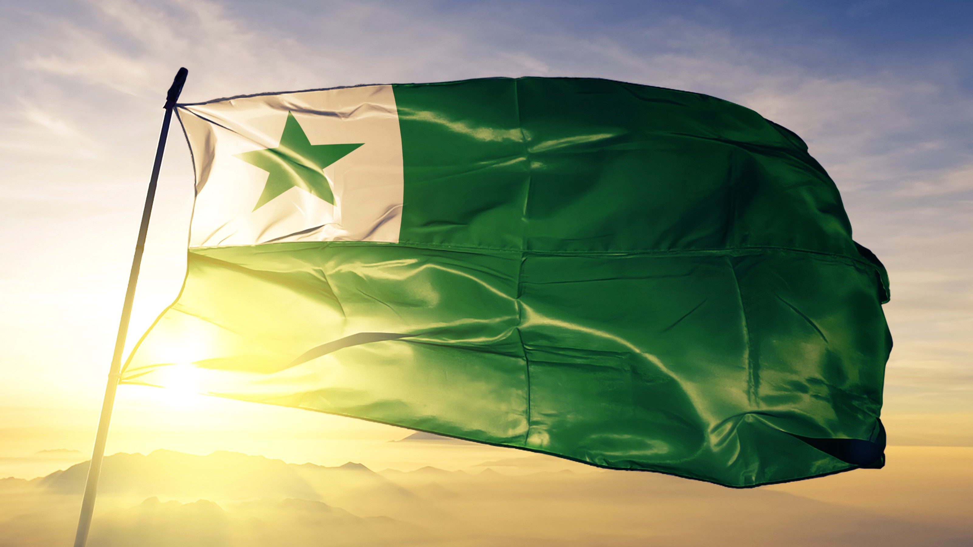 A green flag flutters in the wind with an Esperanto touch.