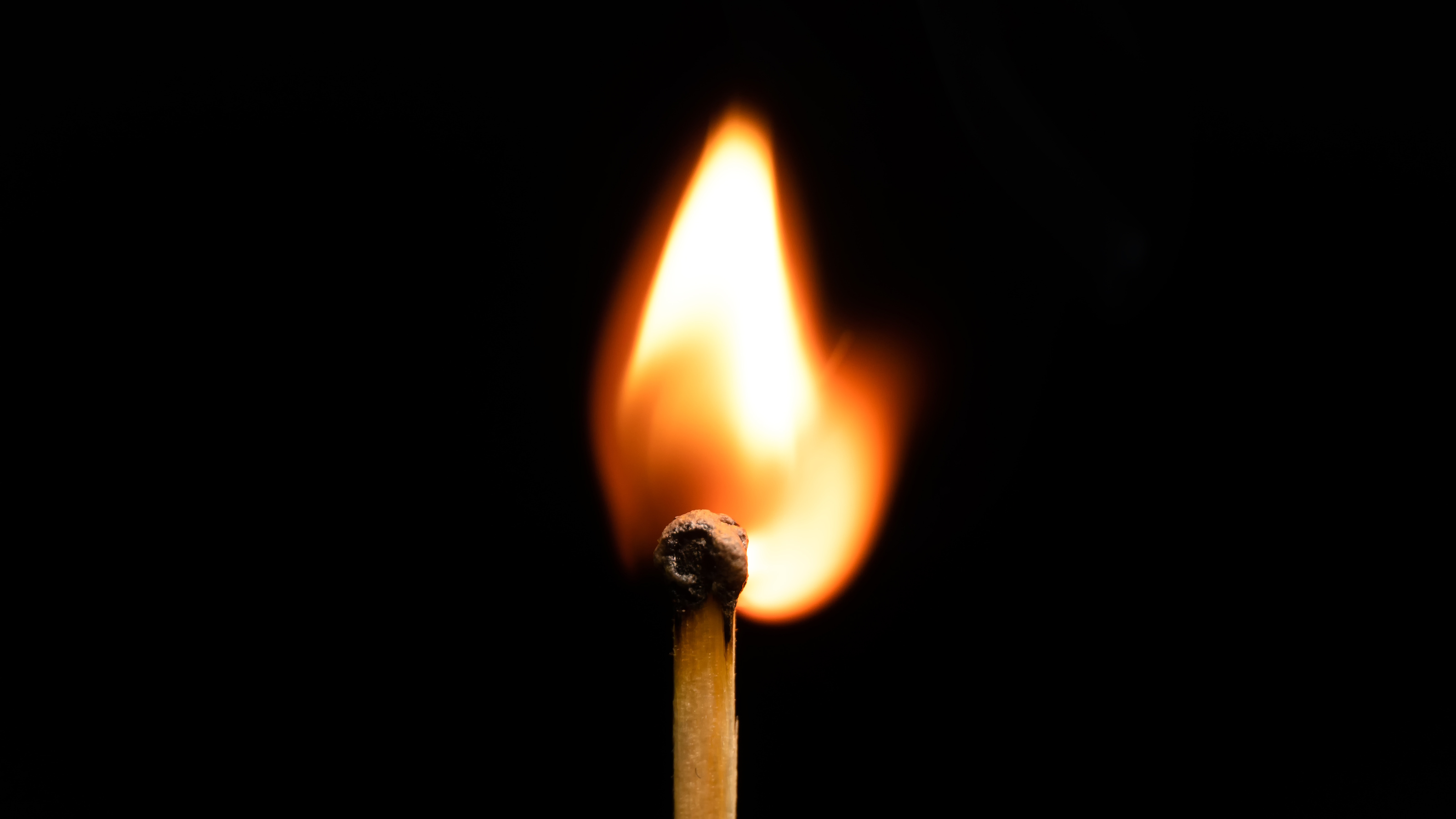 A match stick with a flame on a dark background.