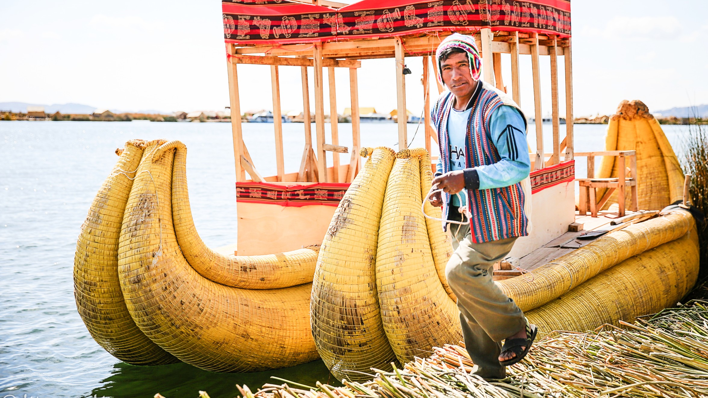 A man standing next to a boat made of bananas at Uros.