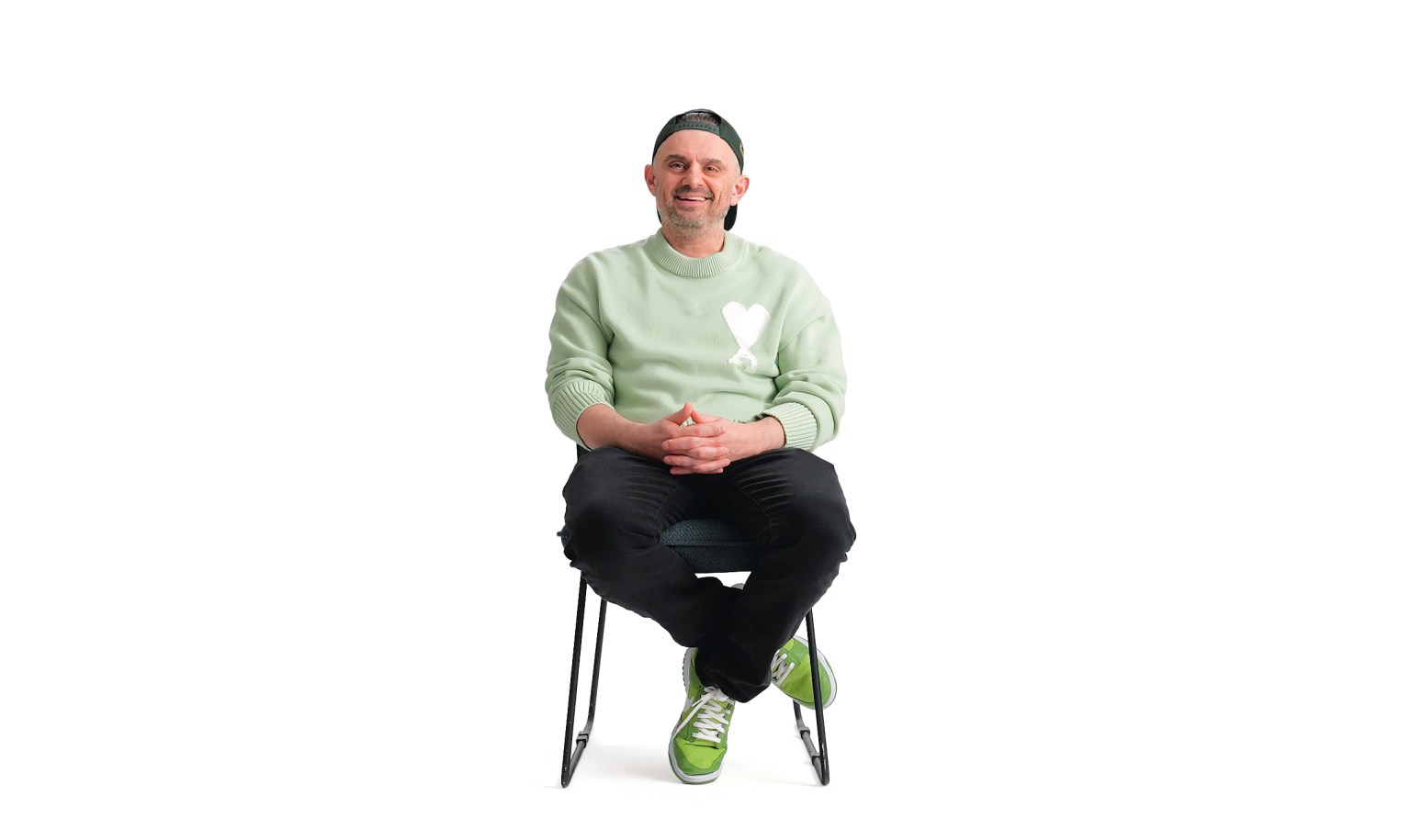 Gary Vee sitting on a chair wearing a green sweater.