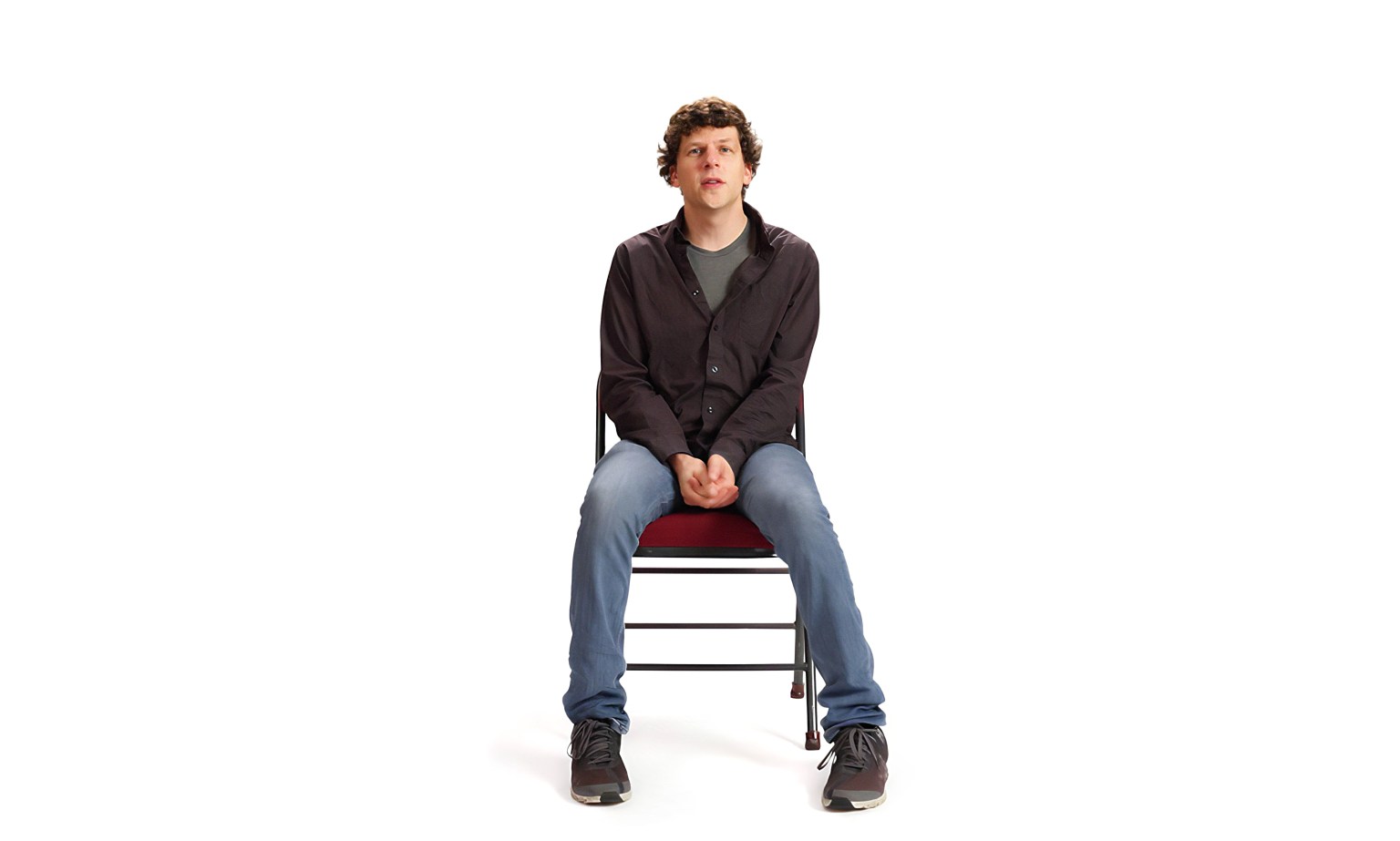 Jesse Eisenberg sitting on a chair.