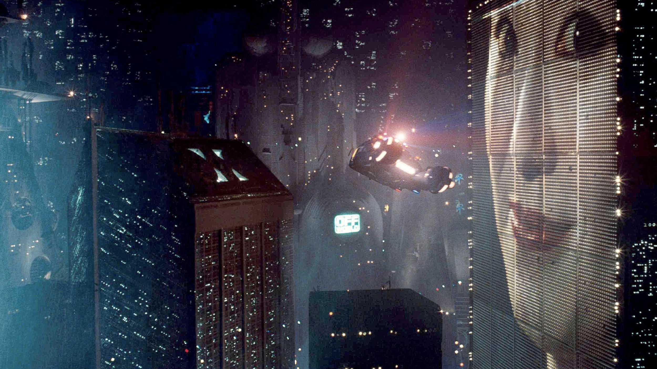 An image of a pop-culture city with a woman in the sky, representing future visions.