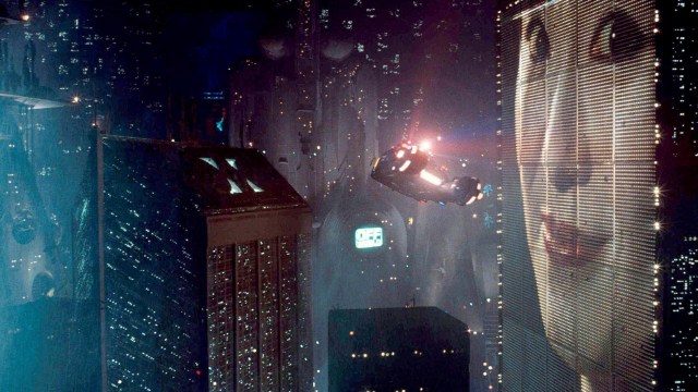 An image of a pop-culture city with a woman in the sky, representing future visions.