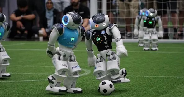A group of robots playing soccer on a field.