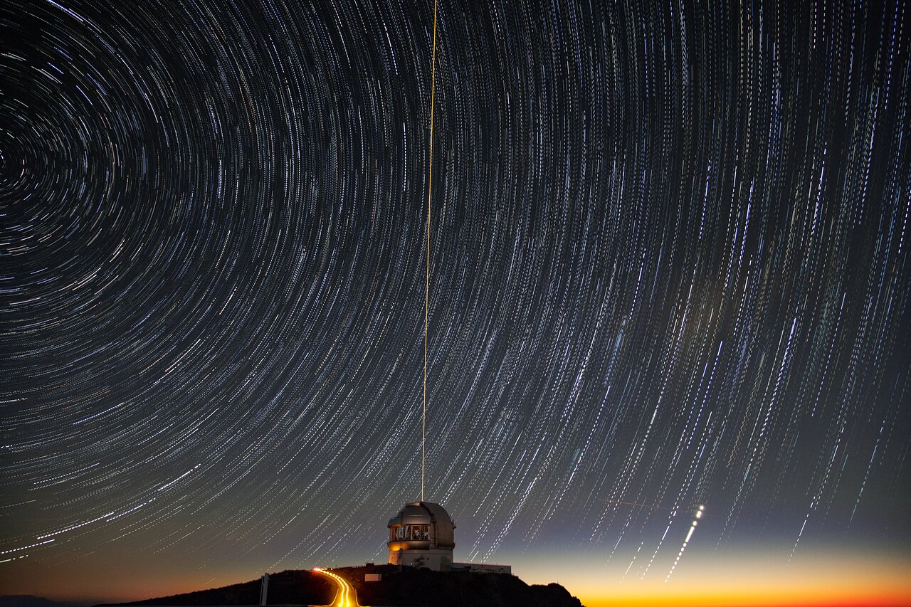 Star trails circle above an astronomy observatory at twilight, overcoming the atmosphere.