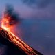 Active volcanoes erupting at twilight, spewing lava and ash.