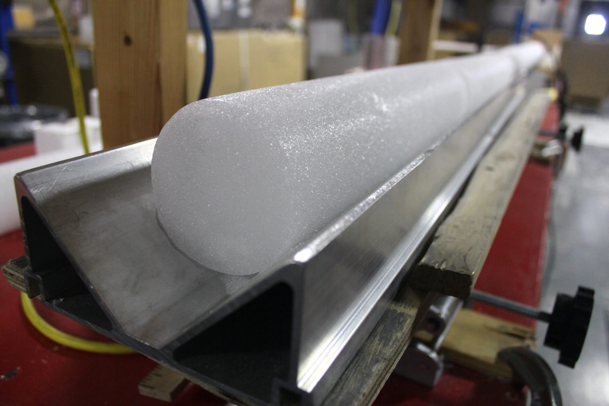 A cylindrical block of ice being extruded from an industrial machine.