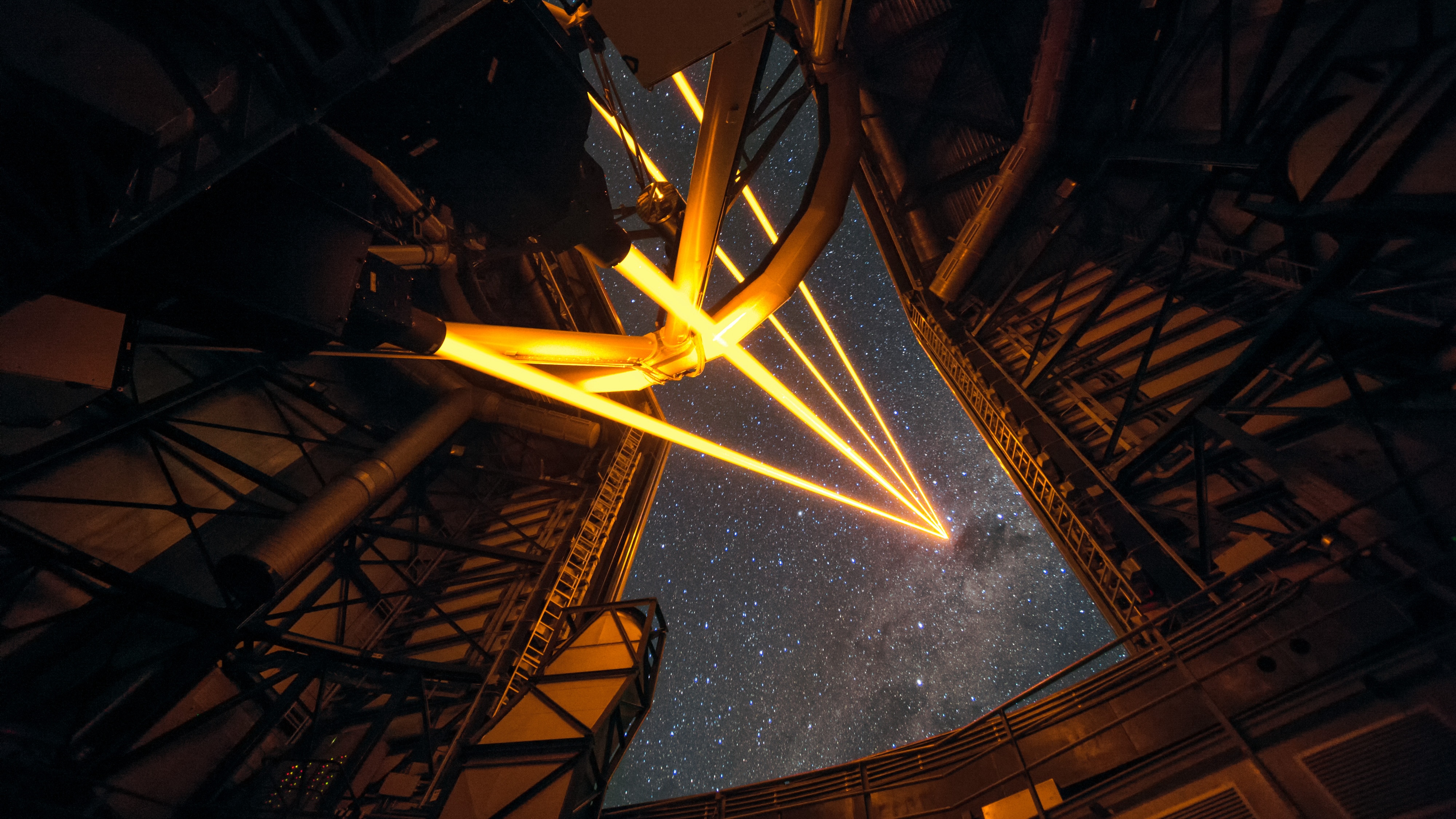 A telescope dedicated to astronomy pointing towards a starry sky at night, with beams of light overcoming the atmosphere to create a visual path.