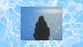 A photo capturing the memory of a woman standing in front of a body of water.