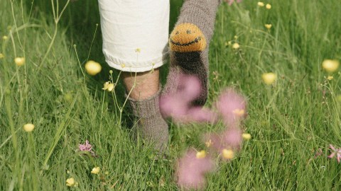 Mismatched socks on feet standing among wildflowers represent unique work-life hacks.