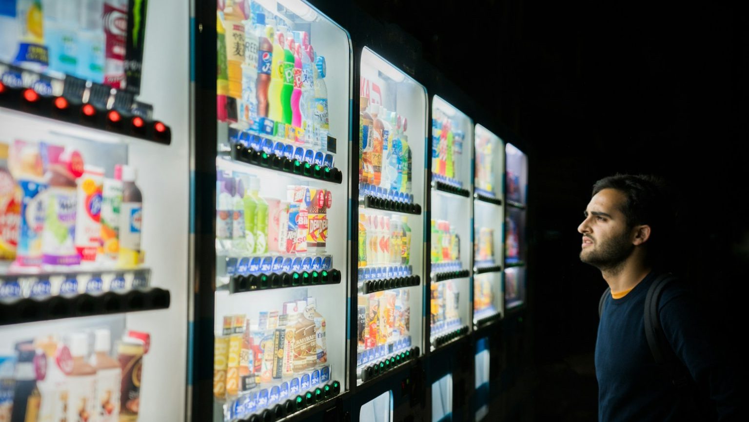 A man looking at a vending machine.