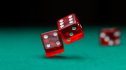 Three red dice in mid-roll on a green surface.