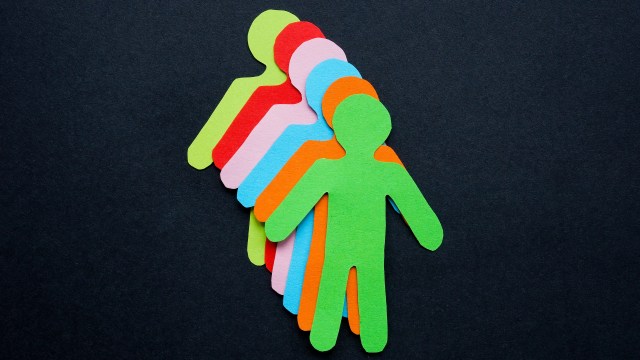 Colorful paper cutouts of human figures in a row on a black background, symbolizing love-based leadership or teamwork.