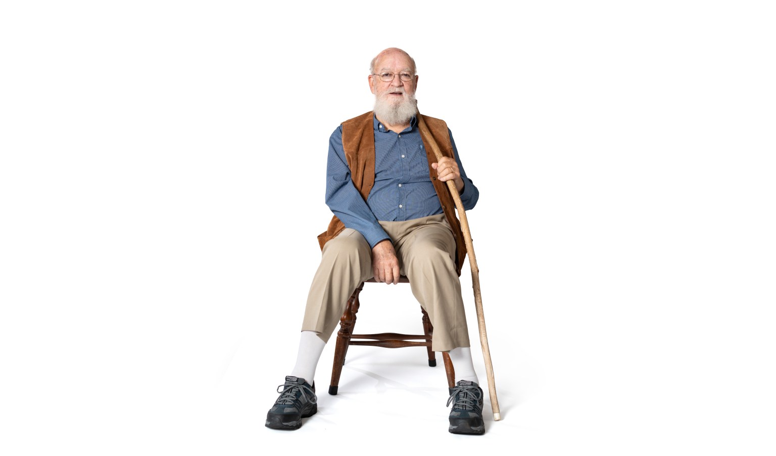 Daniel Dennett sitting in a chair holding a cane.