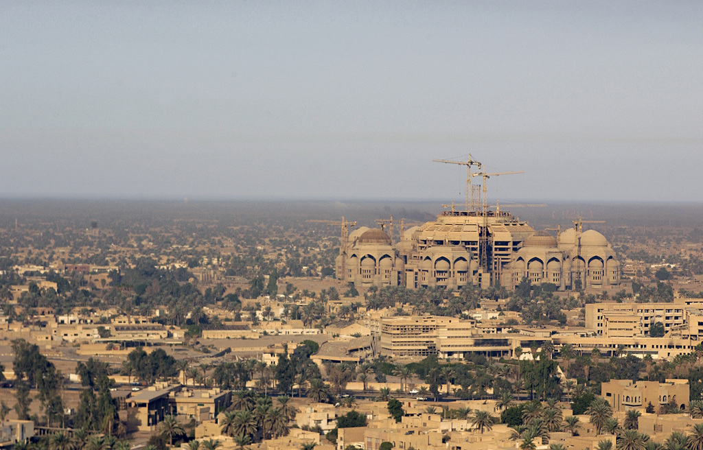 Construction of a large building with domes in progress, overlooking a sprawling cityscape with palm trees as humans transform the earth.