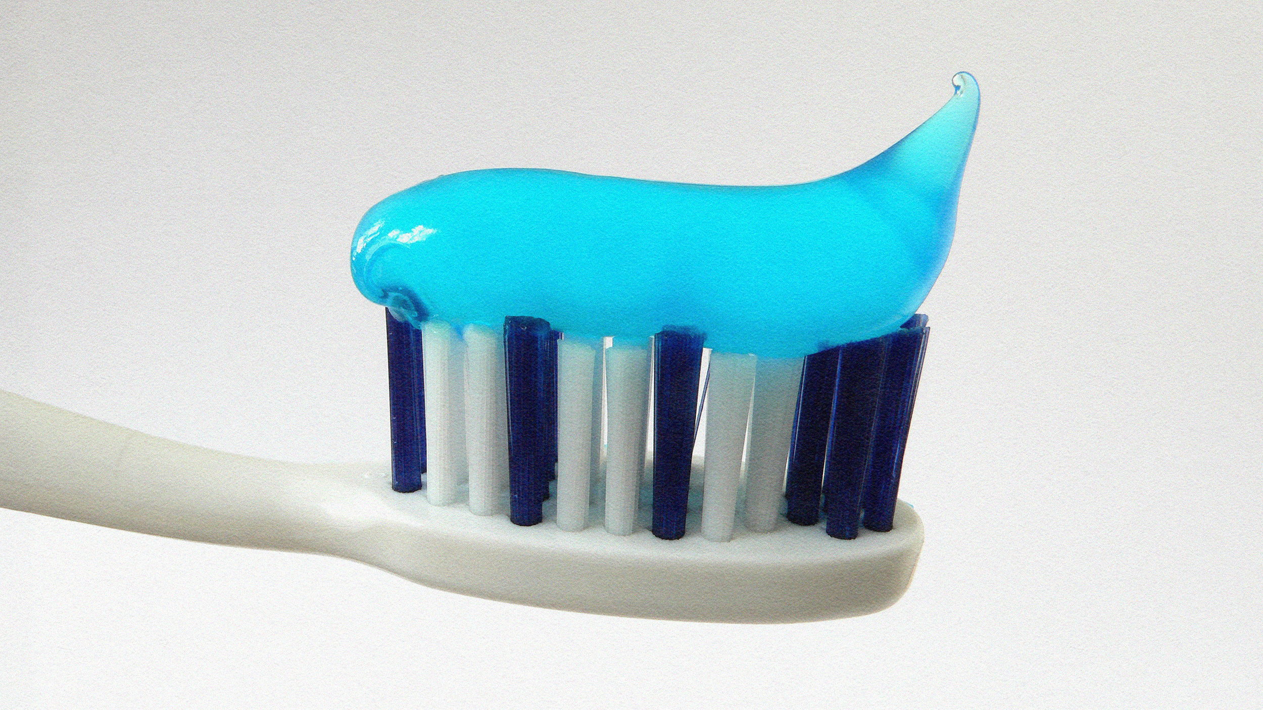 A toothbrush with blue and white bristles, topped with a large dollop of minty toothpaste.
