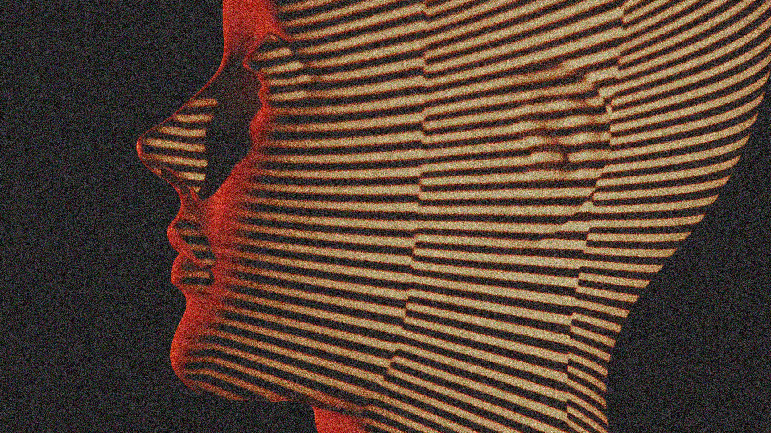 Profile of a person's face with science fiction inspired shadow stripes pattern projected onto it, against a dark background.