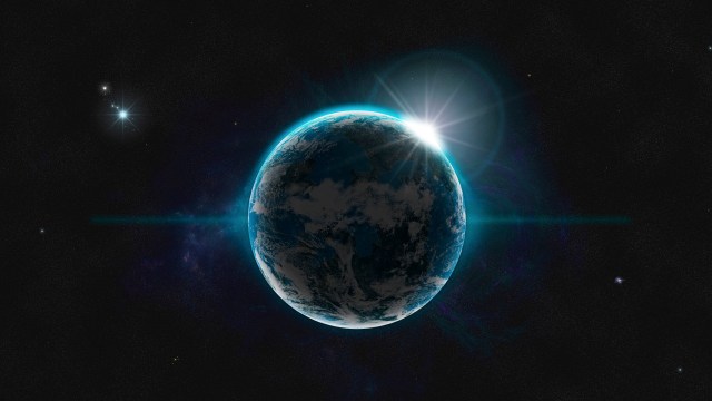 A view of Earth from space with a bright sunburst at the planet's edge. Stars and a dark expanse of space serve as the background.