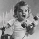 A black and white photo of a young child holding a vintage telephone receiver to their ear, with an excited expression. The background features graphic designs of sound waveforms and orange flames, evoking the intense energy of death metal.
