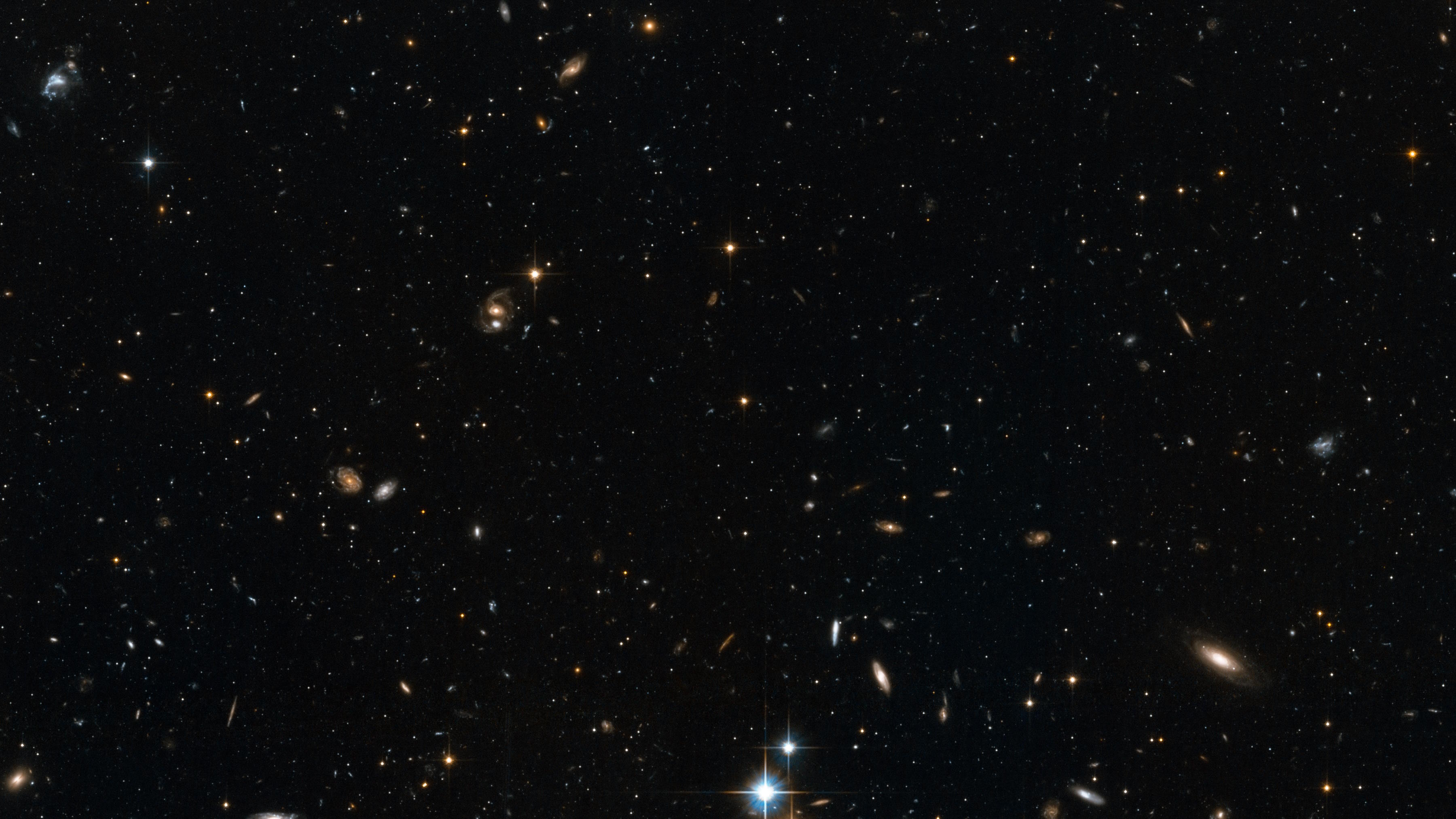 A deep space image showing numerous galaxies of different shapes and sizes scattered across a dark background, with many stars and cosmic objects, including the ancient Methuselah star, also visible throughout.