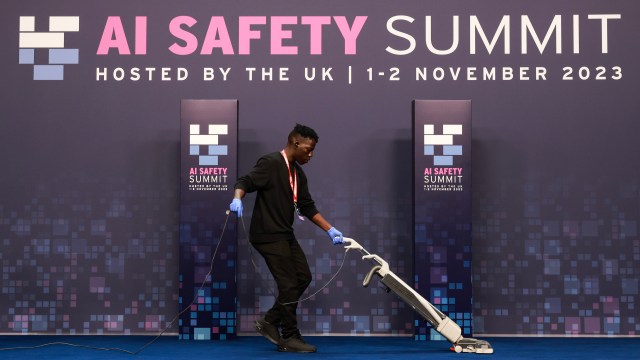 A person vacuuming a blue carpet at the AI Safety Summit hosted by the UK on November 1-2, 2023, where discussions on agentic AI took center stage.