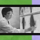 A female physician wearing a lab coat and glasses examines medical images on a lightboard. The background consists of a green and purple abstract design.