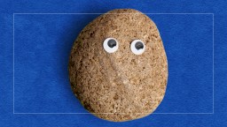 A brown rock with two googly eyes is placed against a blue textured background.