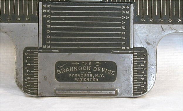 A metal Brannock Device, used for measuring foot size, showing various labeled foot size markings and a plaque indicating it is patented in Syracuse, N.Y.