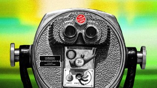 Close-up of a vintage coin-operated binocular viewer with a "Turn to Clear Vision" label, set against a colorful, blurred background.