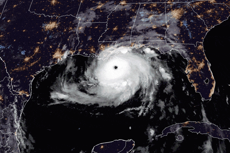 Satellite image of a hurricane, intensified by global warming, making landfall on the Gulf Coast of the United States at night. The storm's eye is clearly visible, and surrounding clouds are illuminated by city lights.