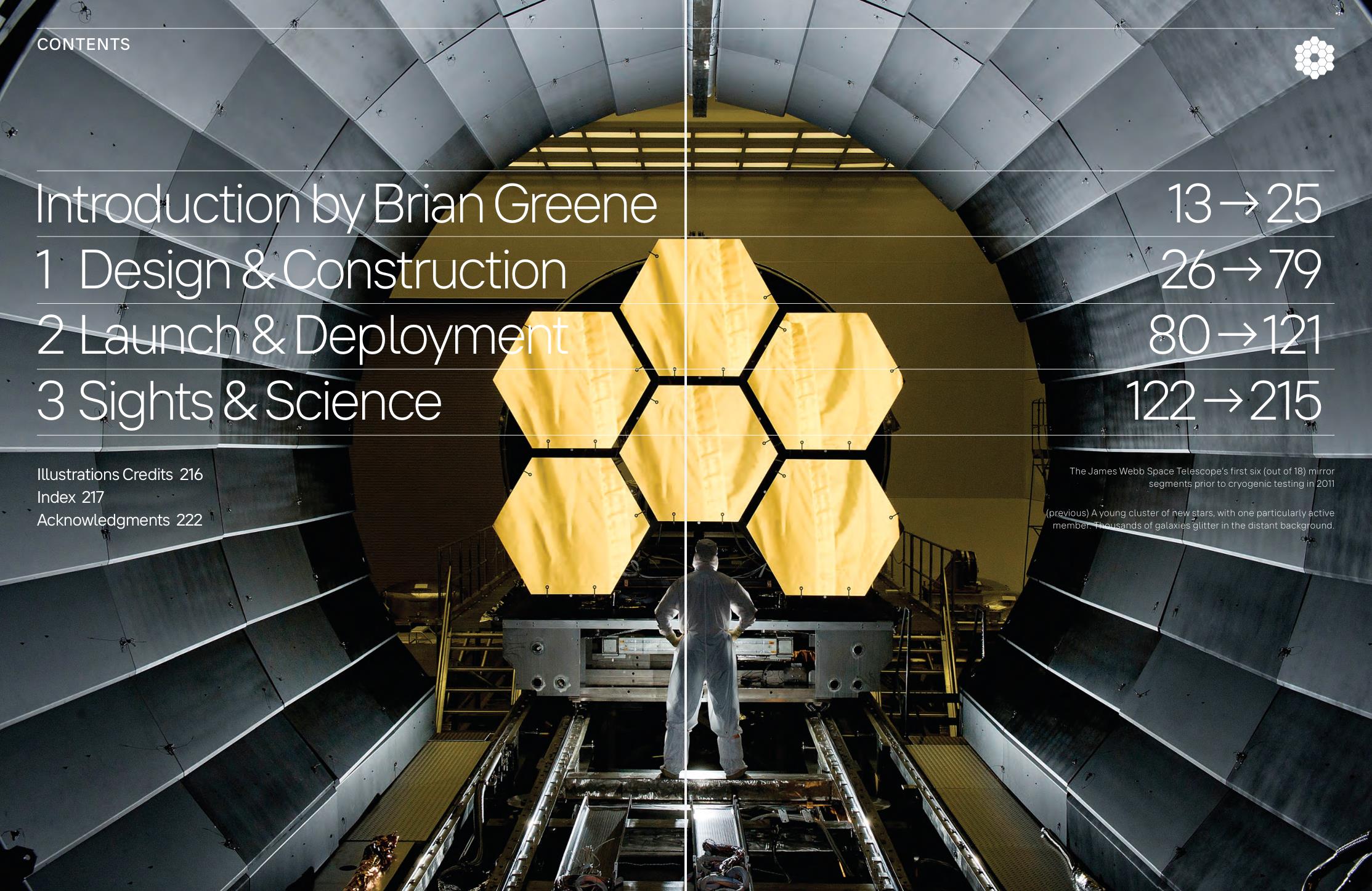 A person stands in front of a large telescope mirror composed of multiple hexagonal segments in an industrial setting.