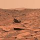 Rocky, reddish Martian landscape with scattered boulders and a hazy sky.