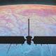 Silhouette of NASA's Europa Clipper spacecraft with antennas poised against a colorful planetary surface, sparking dreams of alien life.