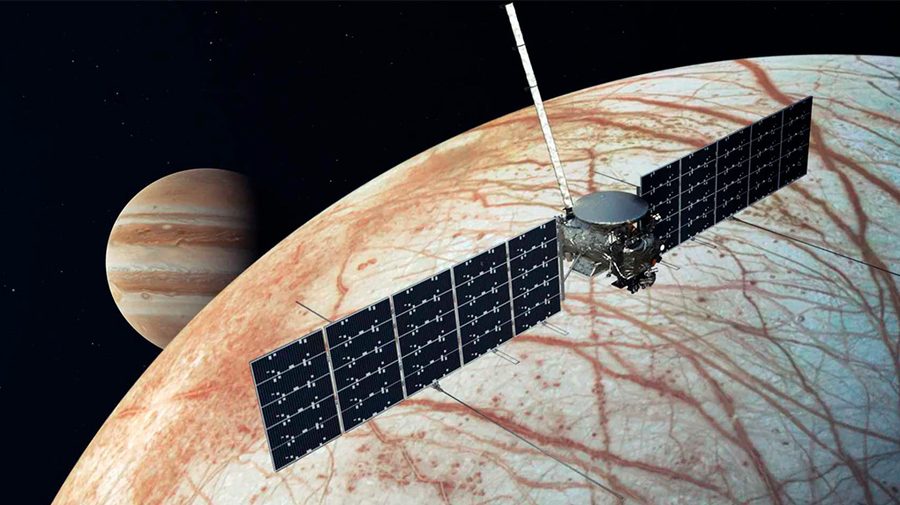 Spacecraft with solar panels orbits Europa, Jupiter's icy moon, with Jupiter visible in the background.