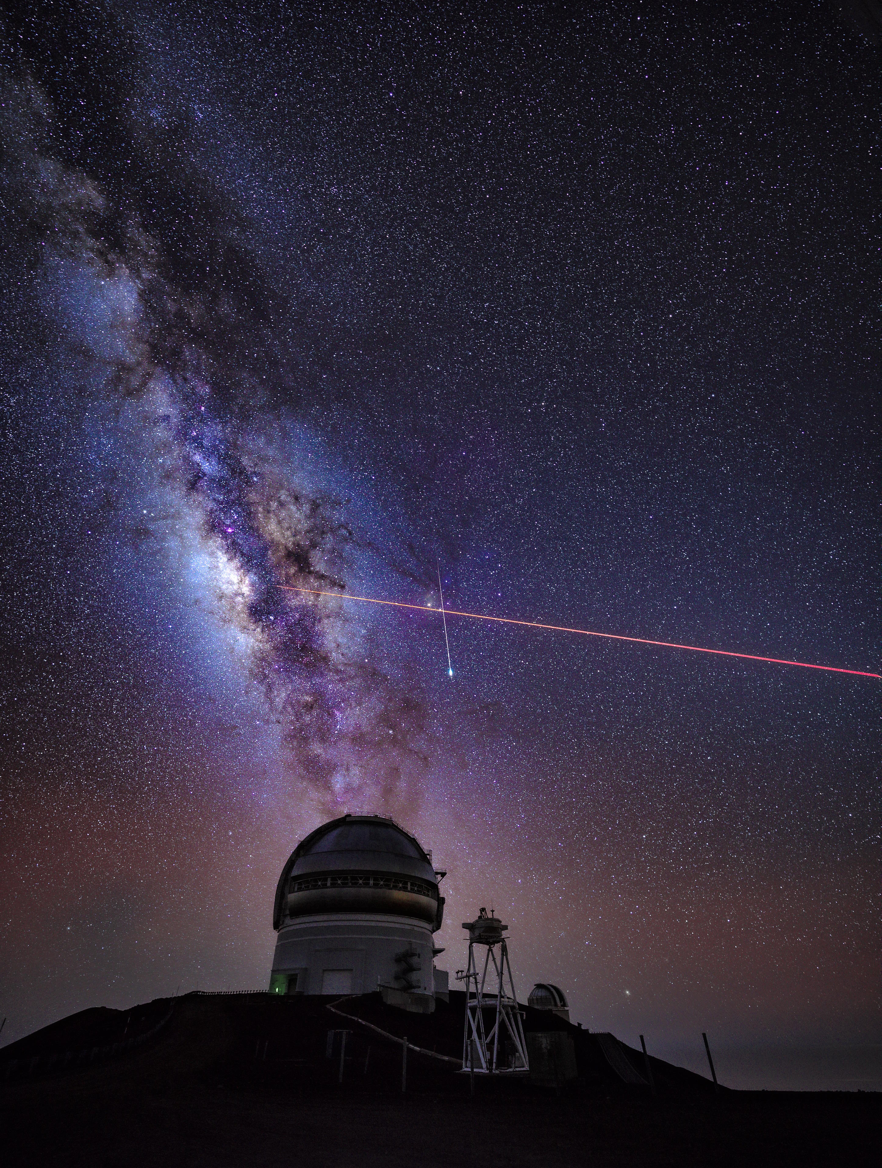 Under a starry sky at one of Earth's best astronomy locations, the Milky Way graces the background while a red light beam crosses the sky.