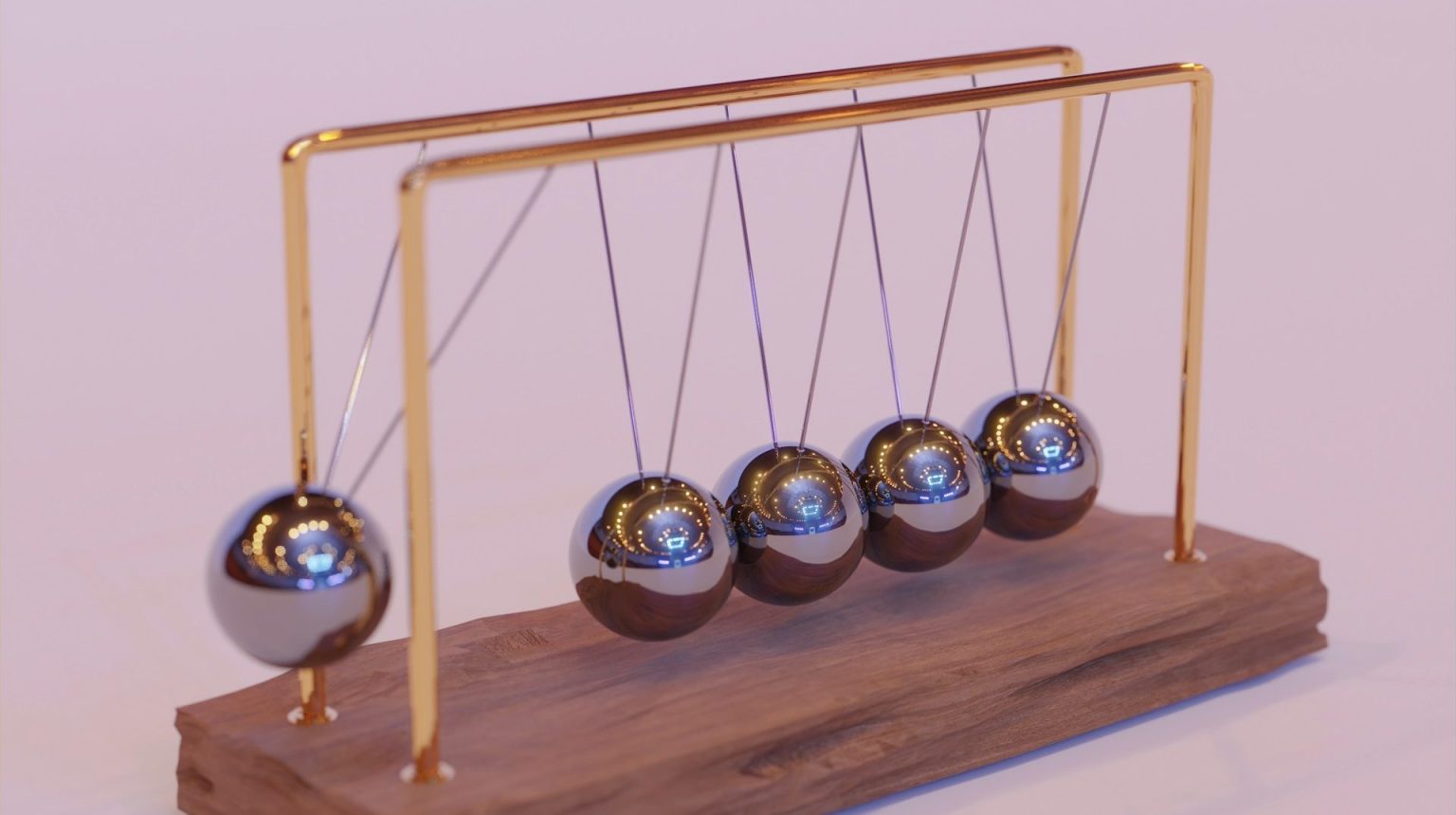 A Newton's cradle with five metal spheres suspended on a wooden base, demonstrating the principles of momentum and energy conservation.